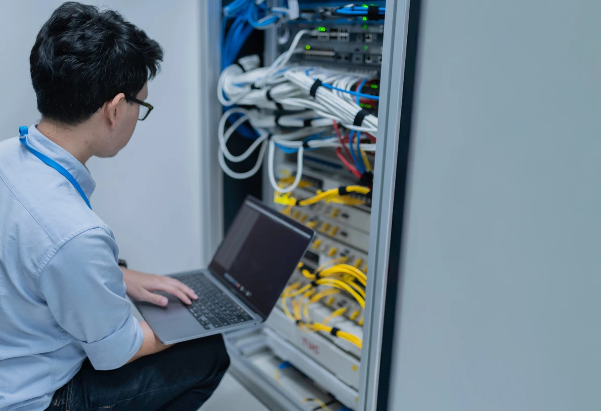 IT engineer working on an on-premises server rack with a laptop