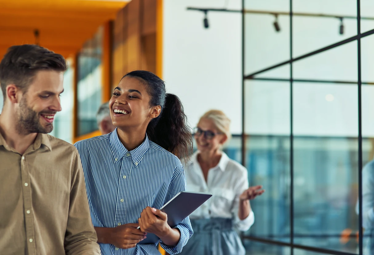 Colleagues walking and talking in a bright office hallway